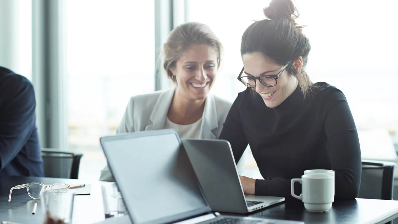 Two colleagues smiling at a laptop in an office (stand-in image, to be replaced with the series line-art banner)